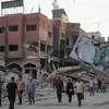 Người dân di chuyển qua những tòa nhà bị phá hủy sau các cuộc không kích của Israel tại Dải Gaza ngày 16/10. (Ảnh: THX/TTXVN)