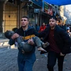 Chuyển em nhỏ bị thương trong vụ oanh tạc của Israel xuống thành phố Rafah, phía Nam Dải Gaza sau khi lệnh ngừng bắn hết hiệu lực, ngày 1/12/2023. (Ảnh: AFP/TTXVN)