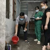 Nhân viên y tế quận Hoàng Mai hướng dẫn người dân vệ sinh môi trường, xử lý khu vực muỗi có thể phát triển sinh sản tại hộ gia đình. (Ảnh: Minh Quyết/TTXVN)