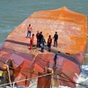 Lực lượng cứu hộ tiến hành móc cáp vào thân tàu Hoàng Phúc 18 để triển khai công tác trục vớt. (Ảnh: TTXVN)