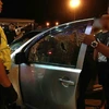 Nạn nhân (che mặt) nói chuyện với cảnh sát bên chiếc xe bị đám 'quái xế​' đập vỡ cửa kính. (Nguồn: nst.com.my)