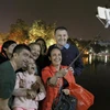 Du khách nước ngoài hào hứng chụp ảnh kỷ niệm thời khắc giao thừa bên hồ Hoàn Kiếm Hà Nội. (Ảnh: Quốc Khánh/TTXVN)