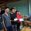 Chủ tịch Hội người Việt Nam tại tỉnh Attapeu Võ Văn Mừng trao tặng số tiền 1 triệu Kip cho 3 gia đình bị ảnh hưởng sau sự cố vỡ đập thủy điện Xe Pian-Xe NamNoy. (Ảnh: Quang Thái/TTXVN)