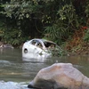 Sau khi lao xuống vực hơn 30m, chiếc xe bị tai nạn ngập trong nước của sông Nậm Rốm. (Ảnh: Xuân Tiến/TTXVN)