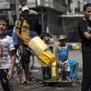 Người dân Palestine xếp hàng lấy nước sinh hoạt tại một trại tị nạn ở Dải Gaza. (Ảnh: AFP/TTXVN)