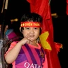Một em bé ở Long An đi cùng với bố mẹ ăn mừng chiến thắng của Đội tuyển Việt Nam. (Ảnh: Bùi Như Trường Giang-TTXVN)
