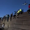 Người di cư vượt qua hàng rào biên giới giữa Mỹ và Mexico, gần cửa khẩu El Chaparral ở Tijuana, bang Baja California, Mexico ngày 25/11/2018. (Ảnh: AFP/TTXVN)