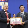 Đại tá Trịnh Vinh Pha, Phó chủ tịch Trung ương Hội hữu nghị Việt Nam-Campuchia (trái) và Phó chủ tịch thứ nhất Thượng viện Campuchia Sim Ka cùng trao quà lưu niệm. (Ảnh: TTXVN)
