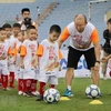 HLV Park Hang-seo hướng dẫn các em học sinh khởi động trước khi chơi bóng đá. (Ảnh: Trung Kiên/TTXVN)