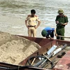 Lực lượng chức năng kiểm tra, xử lý các tàu hút cát trái phép trên sông Lam. (Ảnh: TTXVN phát) 