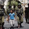 Binh sỹ Israel bắt giữ một cậu bé người Palestine tại khu vực Bờ Tây. (Ảnh: AFP)