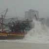 Một tàu cá bị mắc cạn, có nguy cơ bị sóng đánh chìm tại cửa biển Nhật Lệ, thành phố Đồng Hới, tỉnh Quảng Bình. (Ảnh: TTXVN)