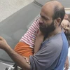Anh Abdul Halim al-Attar bế con nhỏ đi bán bút. (Nguồn: metro.co.uk)