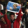Một người nhập cư cầm bức ảnh của Thủ tướng Angela Merkel khi đến Đức. (Nguồn: Getty Images)