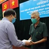 Chủ tịch UBND huyện Hóc Môn trao tiền hỗ trợ cho người bán vé số trên địa bàn. (Ảnh: Tiến Lực/TTXVN)