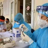 Nhân viên y tế của Trung tâm kiểm soát bệnh tật thành phố Hà Nội tiến hành lấy mẫu xét nghiệm COVID-19. (Ảnh: TTXVN)