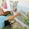 Họa sỹ Đỗ Lệnh Tuấn miệt mài bên bức tranh ghép tem về Chủ tịch Hồ Chí Minh. 