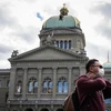 Du khách đeo khẩu trang đi ngang qua Tòa nhà Quốc hội Thụy Sĩ. (Nguồn: AFP)
