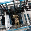 Binh sỹ Ukraine đứng trước một ngôi trường bị phá hủy tại thành phố Mariupol thuộc tỉnh Donetsk. (Nguồn: Aljazeera)