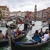 Khách du lịch đi thuyền gondola tại Venice, Italy. (Ảnh: AFP/TTXVN)