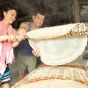 Du khách trải nghiệm làm bánh tráng ở Cần Thơ. (Ảnh: CTV/Vietnam+)
