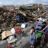 Người dân đi bên đống đổ nát sau khi bão Haiyan đi qua thành phố Tacloban, tỉnh Leyte, miền Trung Philippines ngày 10/11. (Nguồn: AFP/TTXVN)