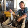 Chị Nguyễn Thị Bình bên thùng cá không bán được trong phiên chợ buổi sáng. (Ảnh: Thanh Thủy/TTXVN)