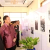 Đại sứ Nguyễn Mạnh Hùng và Bí thư, Tỉnh trưởng Savannakhet, ông Santiphap Phomvihane cùng các quan khách đang đi xem ảnh trưng bày tại triển lãm. (Ảnh: Phạm Kiên/Vietnam+)