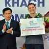 Bộ trưởng Bộ Văn hóa-Thể thao và Du lịch Nguyễn Ngọc Thiện tặng hoa, kỷ niệm chương cho ông Michael Tonge - du khách thứ 10 triệu đến Việt Nam trong năm 2016. (Nguồn: TTXVN)