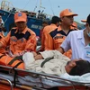 Lực lượng cứu nạn cùng y, bác sỹ hỗ trợ đưa ngư dân đi cấp cứu. (Ảnh: Nguyên Lý/TTXVN)