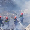Lực lượng chữa cháy tiếp cận hiện trường vụ hỏa hoạn tại thị trấn Lạc Dương (huyện Lạc Dương) vào trưa 1/1. (Ảnh: Nguyễn Dũng/TTXVN)