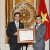 Ủy viên Ban Chấp hành Trung ương Đảng, Thứ trưởng Bộ Ngoại giao Lê Hoài Trung trao Huân chương Hữu nghị cho ông Hồng Tiểu Dũng. (Ảnh: Văn Điệp/TTXVN)