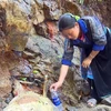 Người dân lấy nước tại mạch nước ngầm ở khu vực chân núi. (Ảnh: Hữu Quyết/TTXVN)