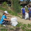 Các em học sinh tham gia nhặt rác tại bãi biển. (Ảnh: Nguyễn Sơn/Vietnam+)