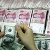 Đồng tiền giấy 100 đôla Mỹ (trên) và đồng 100 nhân dân tệ (phía dưới) tại một ngân hàng ở Hoài Bắc, tỉnh An Huy, Trung Quốc. (Nguồn: AFP/TTXVN)