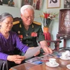 Đại tá Trịnh Xuân Ứng xem lại những kỷ vật xưa. (Ảnh: Hải Yến/TTXVN)