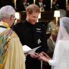 Chú rể Harry (giữa) trao nhẫn cho cô dâu Meghan Markle (phải) tại hôn lễ. (Nguồn: AFP/TTXVN)