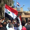 Người dân Syria giương cao quốc kỳ sau khi quân đội giành quyền kiểm soát tỉnh Daraa từ lực lượng nổi dậy ngày 12/7. (Ảnh: AFP/TTXVN)