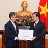Thứ trưởng Bộ Ngoại giao Lê Hoài Trung (bên phải) trao tượng trưng số tiền Chính phủ Việt Nam hỗ trợ Chính phủ, nhân dân Lào khắc phục hậu quả sự cố vỡ đập thủy điện ở tỉnh Attapeu. (Ảnh: Lâm Khánh/TTXVN)