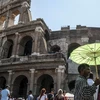 Người dân che ô tránh nắng nóng tại Rome, Italy ngày 2/8. (Ảnh: AFP/TTXVN)