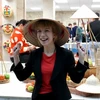 Cô gái Nga thích thú khi đội thử chiếc nón Việt Nam tại ngày hội. (Ảnh: Tâm Hằng/TTXVN)