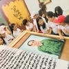 Các em học sinh hào hứng tham quan quyển sách thư pháp viết về Đại tướng Võ Nguyên Giáp. (Ảnh: Võ Dung/TTXVN)