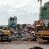  Lực lượng cứu hộ tìm kiếm các nạn nhân và khắc phục hậu quả vụ sập tòa nhà 7 tầng ở Sihanoukville, Campuchia ngày 22/6. (Ảnh: AFP/TTXVN)