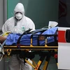 Nhân viên y tế chuyển bệnh nhân nhiễm COVID-19 từ xe cứu thương vào một bệnh viện dã chiến ở Lombardy, Italy ngày 23/3/2020. (Ảnh: AFP/TTXVN)