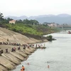 Người dân dựng xe la liệt bên bờ sông Đà để xuống tắm sông, phớt lờ cảnh báo nguy hiểm. (Ảnh: Trọng Đạt/TTXVN)