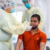 Nhân viên y tế lấy mẫu dịch xét nghiệm COVID-19 cho người dân tại Singapore ngày 15/5/2020. (Ảnh: AFP/TTXVN)
