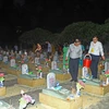 Nghi lễ rải đậu cát tường cầu siêu tại các phần mộ anh hùng, liệt sỹ yên nghỉ ở Nghĩa trang Liệt sỹ Quốc tế Việt-Lào. (Ảnh: Tá Chuyên/TTXVN)