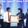 Phó Chủ tịch nước Đặng Thị Ngọc Thịnh, Phó Chủ tịch thứ nhất Hội đồng Thi đua-Khen thưởng Trung ương trao Huân chương Lao động hạng Nhất của Chủ tịch nước cho tập thể Đài Truyền hình Việt Nam. (Ảnh: Dương Giang/TTXVN)