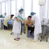 Các bác sỹ khoa Nhi, Bệnh viện Đa khoa tỉnh Sơn La thăm khám cho các bệnh nhi nhập viện sau khi tiêm vắcxin. (Ảnh: Hữu Quyết/TTXVN)