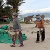 Người dân vận chuyển vật dụng kinh doanh trên các bãi biển đưa lên bờ để tránh thiệt hại khi bão số 9 đổ bộ. (Ảnh: Trần Lê Lâm/TTXVN)